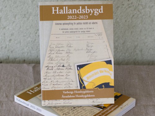 Boken Hallandsbygd 2022–2023. Omslagsbilden är en namnlista med kvinnonamn från Köinge 1913 och den gula fanan med texten ”Rösträtt för kvinnor” som var rösträttsrörelsens emblem.